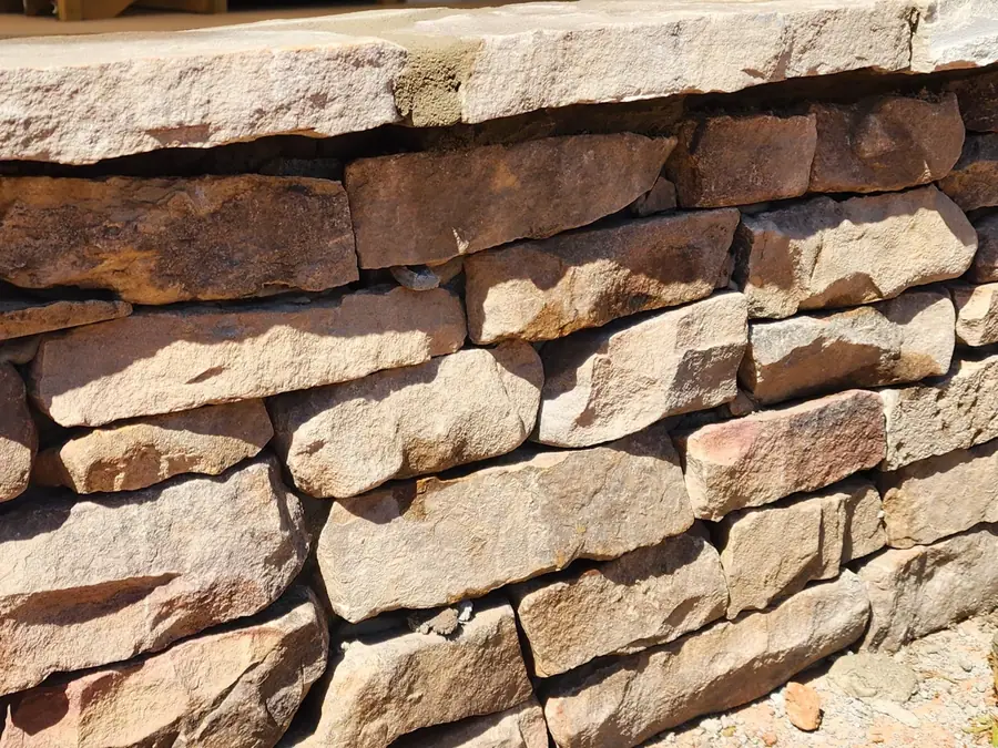 Tan and brown fieldstone laid in a tight running bond — this is what thirty years of hand-fitting looks like. Part of a 1940s farmhouse restoration in Greer, using modern materials to bring back its original character.